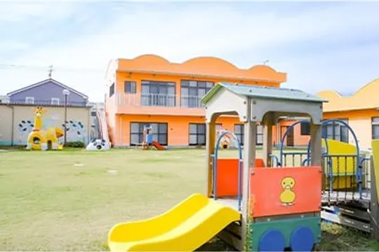 オレンジの園舎と遊具のある園庭