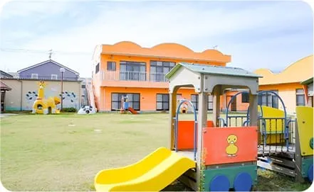 オレンジの園舎と遊具のある園庭