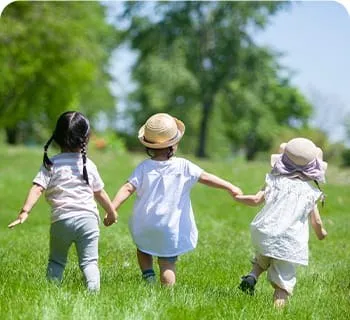 草原で手をつないで走る3人の子ども