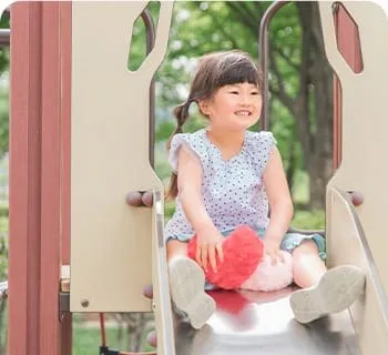 滑り台に座って笑う女の子
