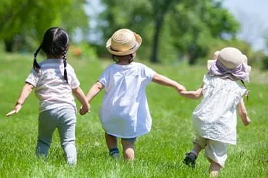 草原で手をつないで走る3人の子ども