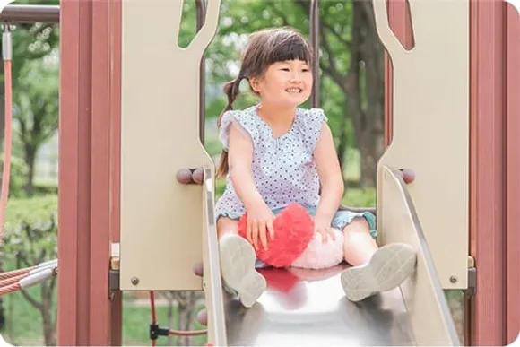 滑り台に座って笑う女の子