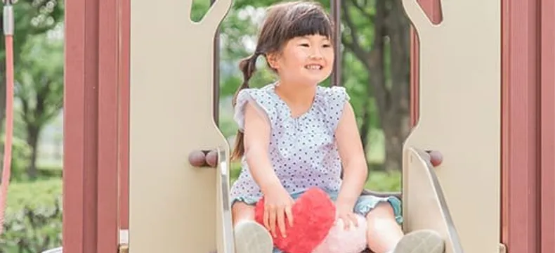滑り台に座って笑う女の子