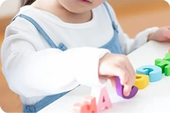 アルファベットのブロックで遊ぶ子どもの手元